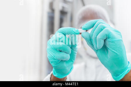 Lavoratore farmaceutica esaminando pillola. Fabbricazione di prodotti farmaceutici di ispezione di una pillola o compressa. Foto Stock