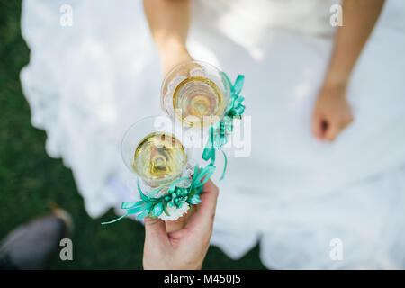 La sposa e lo sposo bere champagne sull'erba Foto Stock