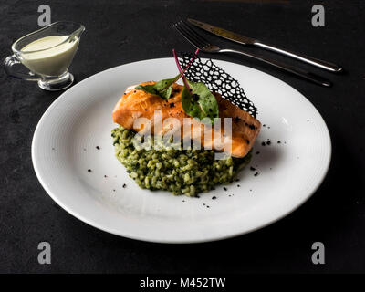 Salmone fritto sul risotto con spinaci Foto Stock