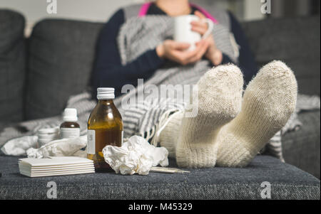 Medicina fredda e malata di bere bevande calde per ottenere così da flu, febbre e virus. Sporchi di asciugamani di carta e tessuti sulla tabella. Persona malata. Foto Stock