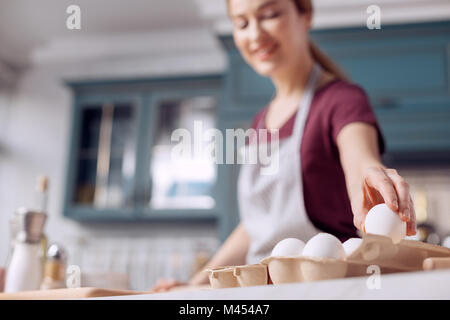 Piacevole giovane donna prendendo uovo dal cartone uovo Foto Stock