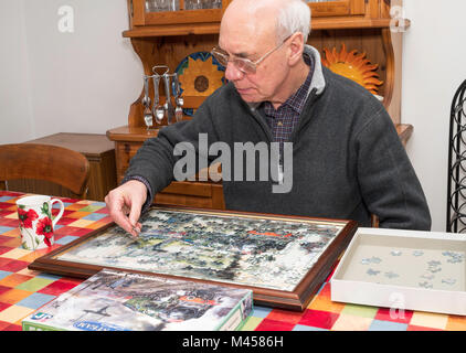 Uomo anziano completando puzzle Foto Stock