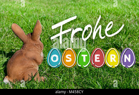 Frohe Ostern (in tedesco felice Pasqua) con uova colorate e il coniglietto di pasqua sul prato. Foto Stock