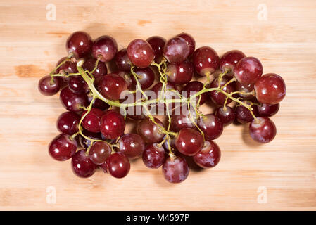 Le uve rosse con piccioli sulla tavola di legno sfondo. rosso uve fresche Foto Stock