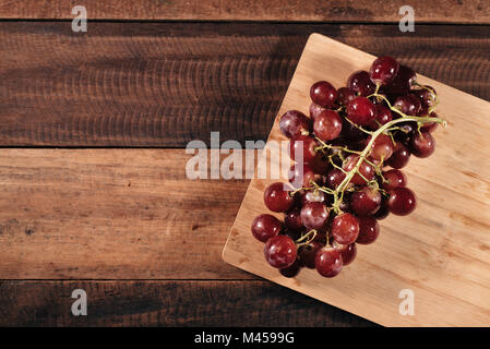 Le uve rosse con piccioli sulla tavola di legno sfondo. rosso uve fresche Foto Stock