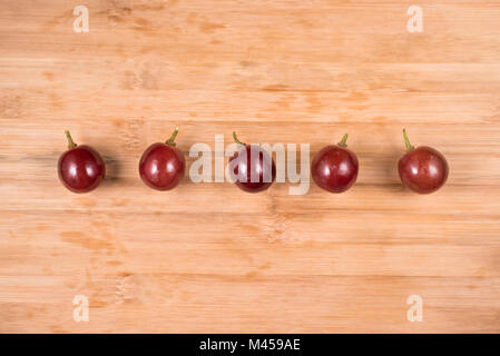 Le uve rosse con piccioli sulla tavola di legno sfondo. rosso uve fresche Foto Stock