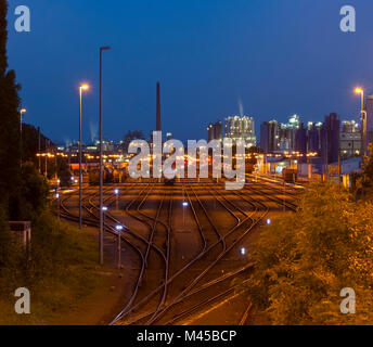 Night Shot di un industriale cantiere ferroviario con diversi treni, una raffineria in background. Foto Stock