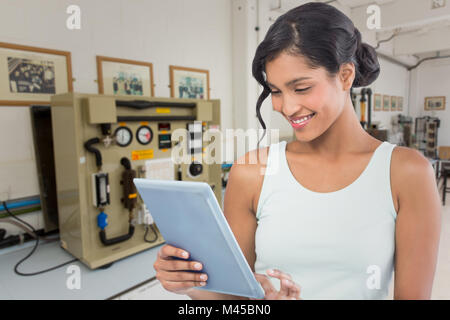 Immagine composita di sorridere imprenditrice utilizzando tavoletta digitale Foto Stock