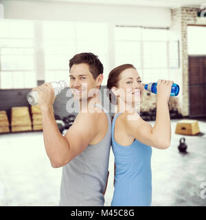 Immagine composita di felice montare giovane coppia con bottiglie di acqua Foto Stock