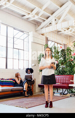 Ritratto di donna in piedi in ufficio guardando sorridente della fotocamera Foto Stock