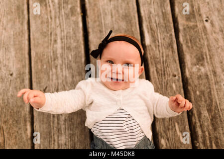 Ritratto di overhead di bambina giacente su tavole di legno Foto Stock