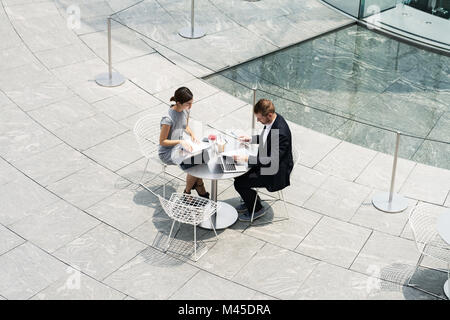 Giovane imprenditrice e uomo incontro al cafè sul marciapiede, ad alto angolo di visione Foto Stock