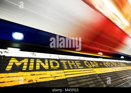 La metropolitana di Londra. Mente il divario segno, treno in movimento. Foto Stock