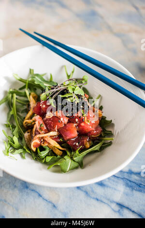 Tonno Poke sulla parte superiore delle foglie di rucola con hijiki e microgreens. Foto Stock