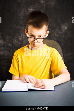 Ragazzo che facce mentre studiava per i compiti a casa Foto Stock