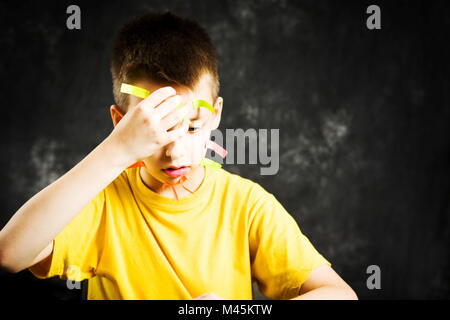 Scuola di occupato ragazzo con la faccia coperta in faccende di adesivi Foto Stock