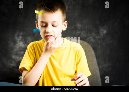 Scuola di occupato ragazzo con la faccia coperta in faccende di adesivi Foto Stock