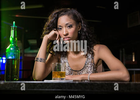 Premuto donna avente whiskey al bancone bar Foto Stock