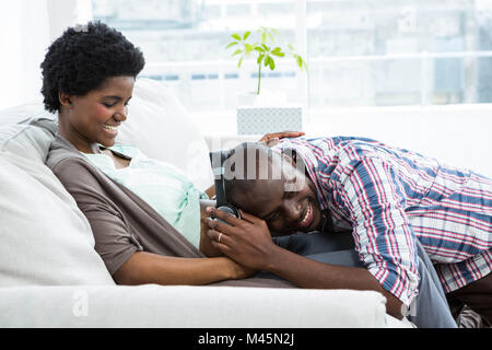 Uomo con le cuffie sulla gravidanza womans stomaco Foto Stock