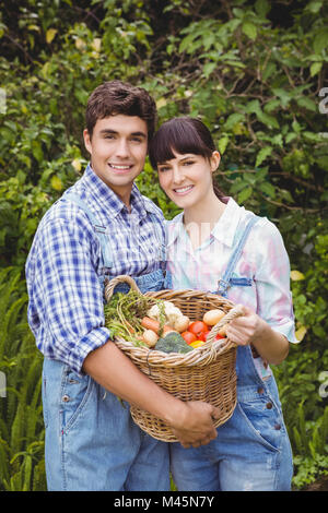 Coppia giovane tenendo un paniere di appena raccolto di ortaggi Foto Stock