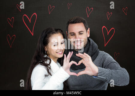 Immagine composita della coppia sorridente messa a forma di cuore con le mani Foto Stock