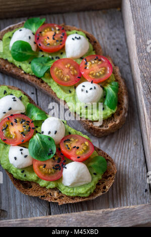 Panini con pasta di avocado, pomodorini e mozzarella Foto Stock