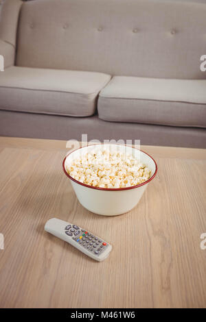 Ciotola di popcorn e televisione remote sul tavolo Foto Stock