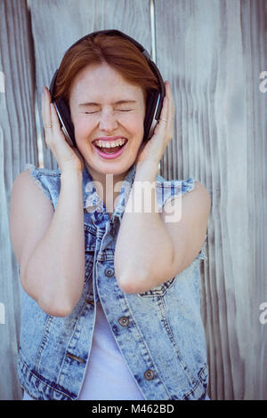 Tanga sorridente donna ascoltando la musica attraverso le cuffie Foto Stock