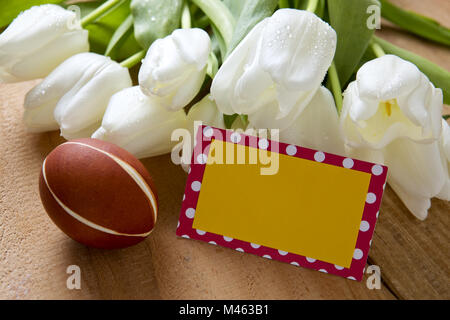 Uovo di Pasqua e tulipani bianco su un tavolo di legno. Foto Stock