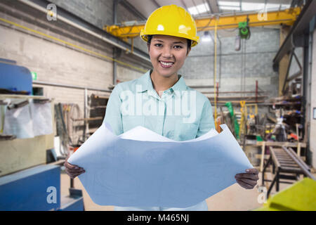 Immagine composita di architetto la lettura di un piano con casco giallo Foto Stock