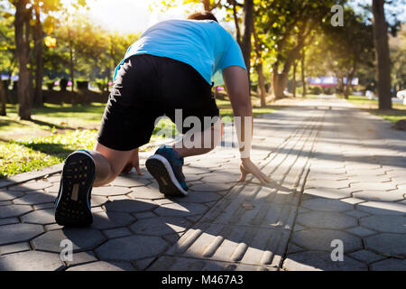 Pronti per andare! Close up tagliate ad angolo basso foto di scarpa di atleta uomo in esecuzione di avviare pongono sulla strada nel parco. Foto Stock