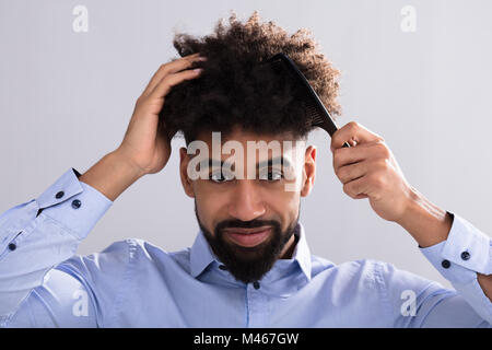 Ritratto di un giovane uomo di pettinare i capelli con il pettine per capelli Foto Stock