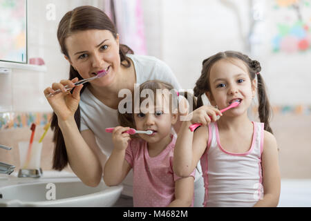 Madre di due bambini di spazzolamento dei denti nella stanza da bagno Foto Stock