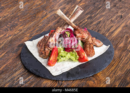 Ribeye sull'osso, Tomahawk, servita con pomodori e lattuga iceberg sulla pita sulla scheda di ardesia. Foto Stock