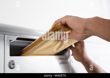 Close-up di un portalettere mettendo mano lettere nella casella di posta Foto Stock