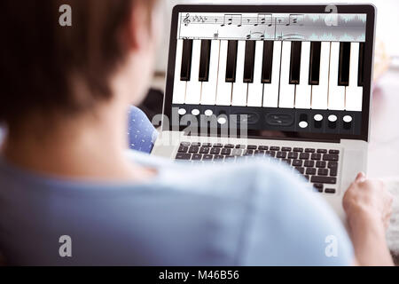 Immagine composita della donna incinta usando il suo computer portatile Foto Stock