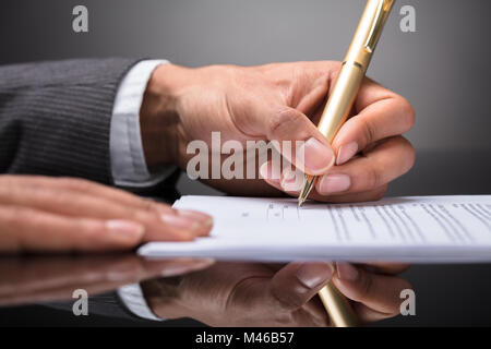 Close-up di un giudice la scrittura sul documento con penna Foto Stock