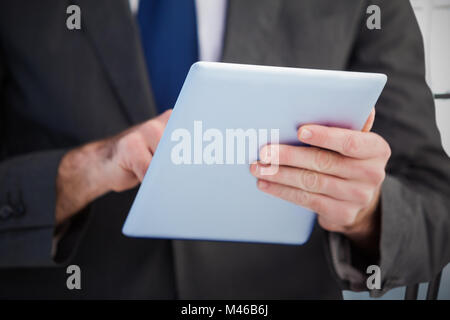 Immagine composita di imprenditore a scorrere sul suo tavoletta digitale Foto Stock