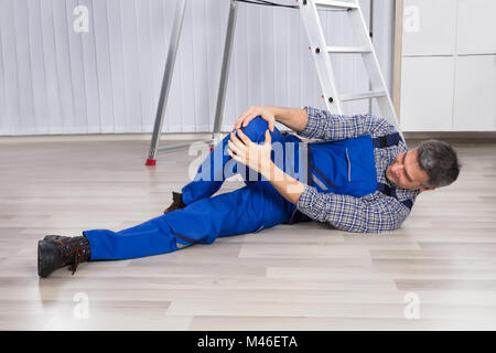 Un uomo ferito subito dal dolore alle gambe mentre giaceva sul pavimento di legno duro Foto Stock
