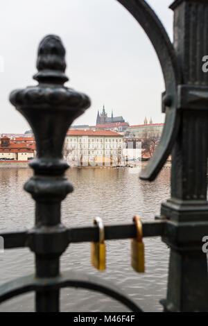 Vista del fiume Moldava e sul castello di Praga dall'altro lato del fiume attraverso la recinzione con amore si blocca Foto Stock