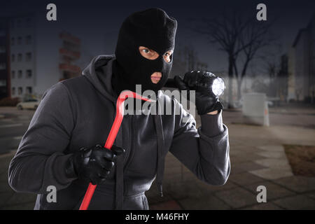 Ladro con un palanchino e una torcia in piedi su una banchina Foto Stock