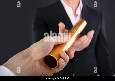 Close-up di un imprenditore passando il relè d'oro testimone a un collega Foto Stock