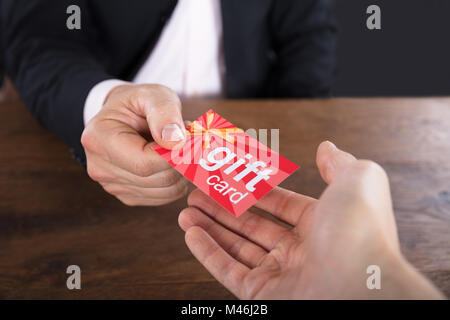 Close-up di un imprenditore mani dando carta regalo per altri commercianti Foto Stock