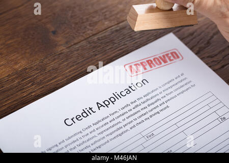 Angolo di Alta Vista di una persona in possesso di timbro di approvazione sul modulo di richiesta di credito Foto Stock