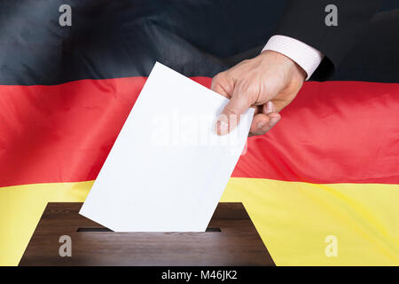 Close-up di una persona di mettere in votazione a scrutinio nella scatola anteriore della bandiera tedesca Foto Stock