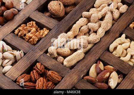 Vari dadi selezione: arachidi, nocciole, castagne, noci, pistacchi e le noci pecan in una scatola di legno. Vista superiore Foto Stock