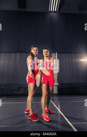 Giovani donne in posa dopo aver giocato a badminton in palestra Foto Stock