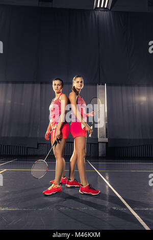 Giovani donne in posa dopo aver giocato a badminton in palestra Foto Stock