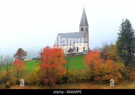 Chiesa di Santa Maddalena in autunno la nebbia. Val di Funes, Alto Adige, Dolomiti, Italia Foto Stock