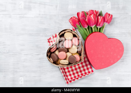 Red tulip bouquet di fiori e amaretti in cuore confezione regalo su sfondo di legno. Il giorno di San Valentino biglietto di auguri. Vista da sopra con lo spazio per i messaggi di saluto Foto Stock